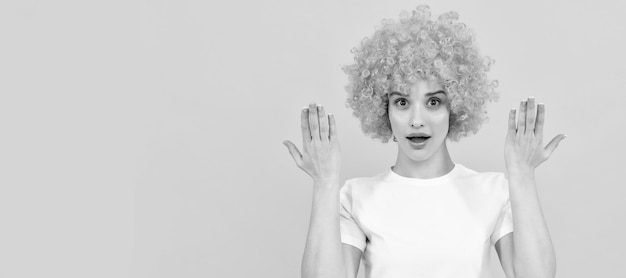 Surprised freaky woman in curly clown wig with raised hands surprise Woman isolated face portrait