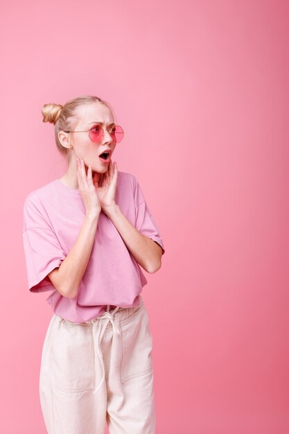 Surprised girl in glasses on pink