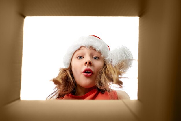 Foto ragazza sorpresa che guarda nella scatola dei regali di natale