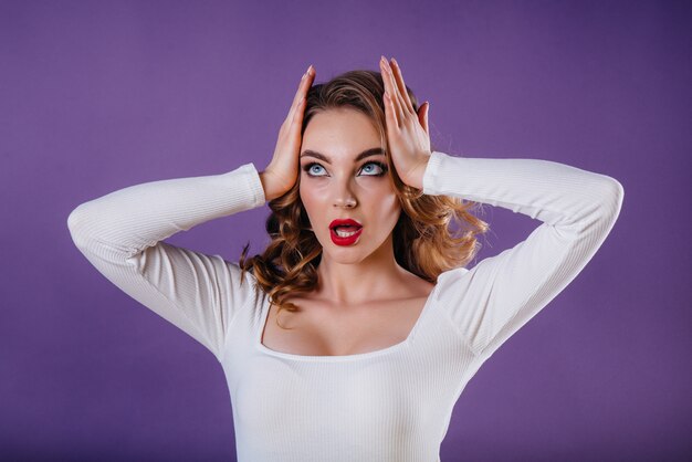 surprised girl posing in studio with purple wall