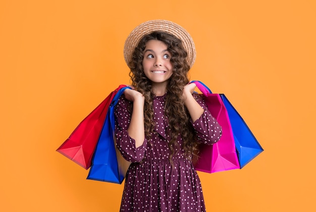 surprised girl with curly hair hold shopping bags on yellow background