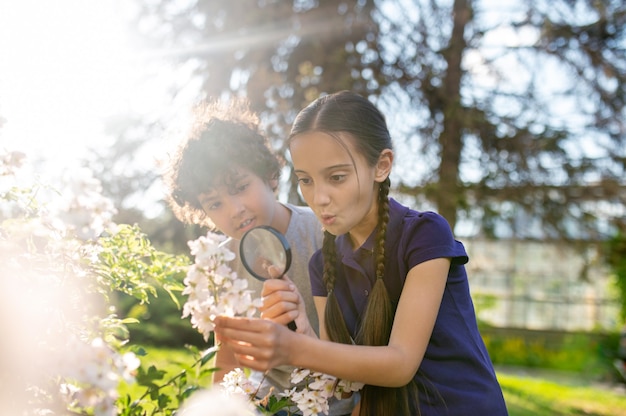 Surprised girls with magnifying glass and boy