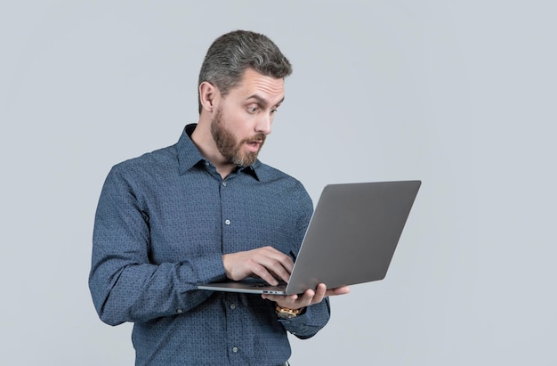 surprised handsome mature man businessman with beard working online on laptop, business.