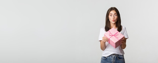 Foto ragazza sorpresa di buon compleanno che riceve il fondo bianco del regalo avvolto