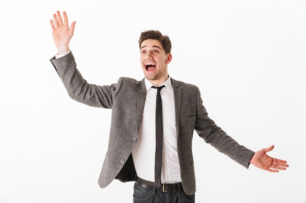 Surprised happy business man in jacket waving his palm and looking away over white wall