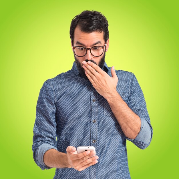 Surprised hipster man talking to mobile on colorful background