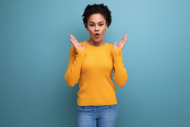 Surprised joyful young brunette latin female adult in yellow sweater is happy