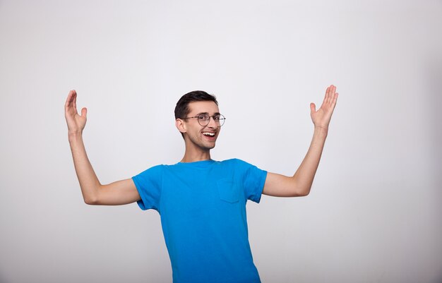 Surprised joyful young man in a blue T-shirt on a white.