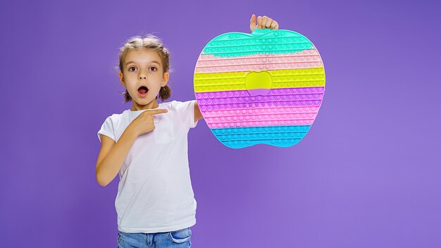 Surprised kid holding huge apple anti stress bubble motor skills pop it fun child holding color popi...