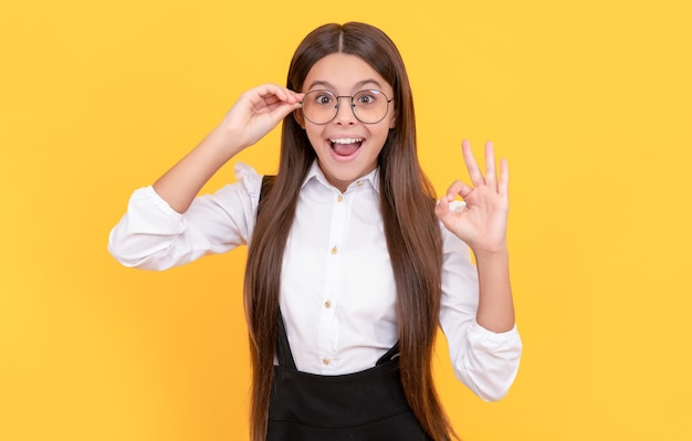 Surprised kid in school uniform and glasses for vision protection waving hello eyeglasses