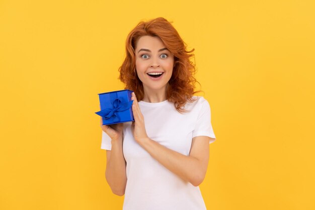 Surprised lady with purchase box on yellow background shopping