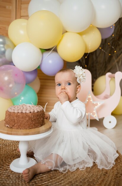 Una bambina sorpresa mangia una torta con la crema su un supporto con le sue mani