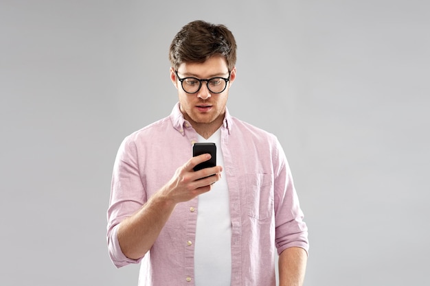 Photo surprised man in glasses looking at smartphone