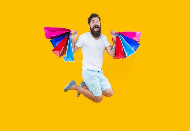 Surprised man jump at shop with bags shopper man jump with\
beard shop purchase concept