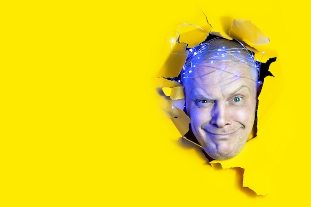 Photo surprised man looking through hole in yellow paper background