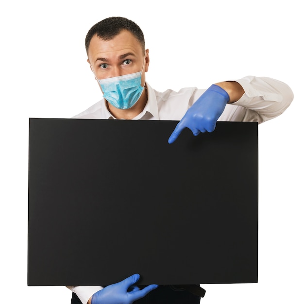 Surprised man in a medical mask and gloves shows his index finger down to the place for text