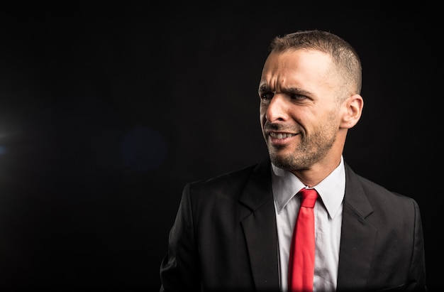 Surprised man in suit. Black background, close up.