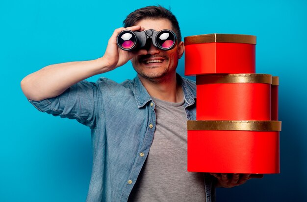 Surprised man with binoculars and red gifts