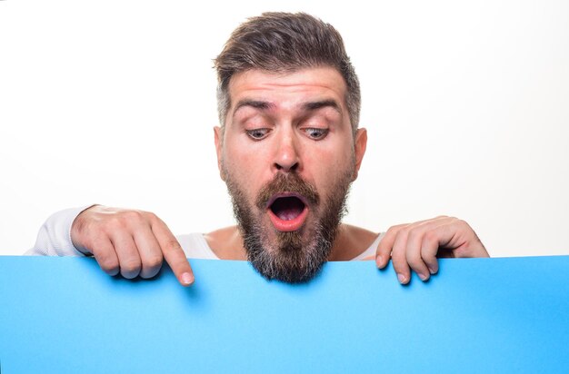 Surprised man with blank poster with space for text bearded man presenting empty advertising banner