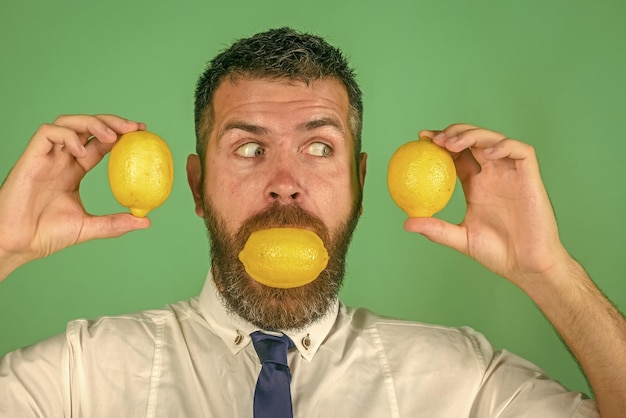 長いひげを生やした驚いた男がレモンを食べる