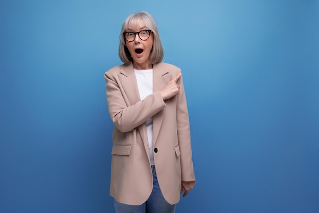 Surprised middleaged s woman in a stylish laconic jacket on a studio background with copy space