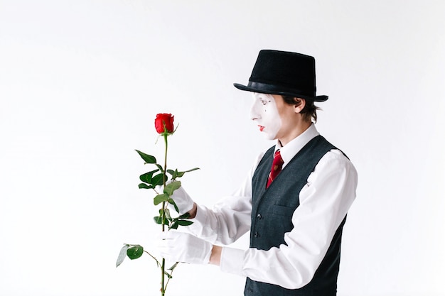 Surprised mime looks at red rose