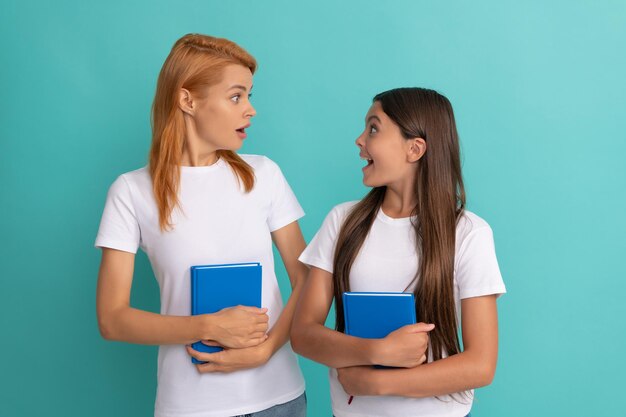 Surprised mother and daughter hold book ready to study education