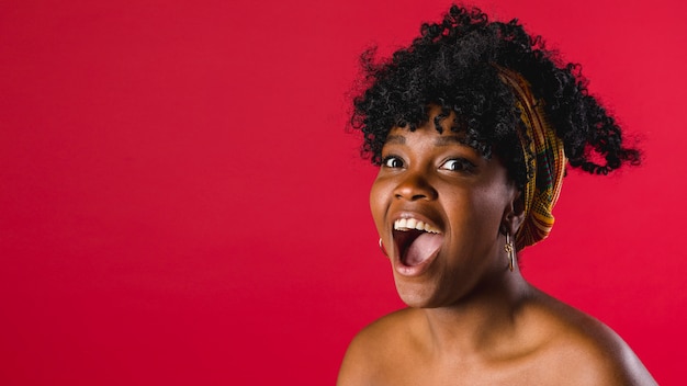 Surprised naked young black woman in studio with bright background