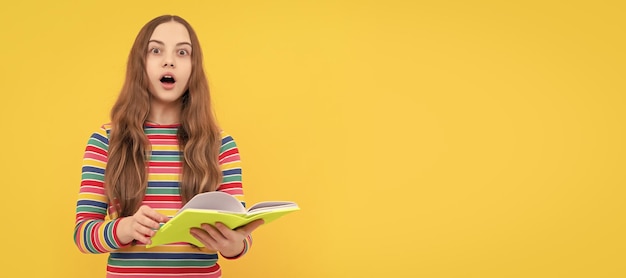 Surprised openeyed kid hold school book yellow background surprise Portrait of schoolgirl student studio banner header School child face copyspace