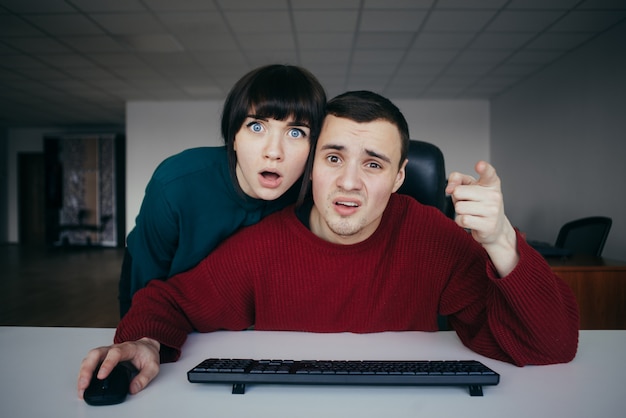 Foto le persone sorprese dal punto di vista emotivo gli impiegati lo hanno visto sullo schermo del computer sullo sfondo dell'ufficio