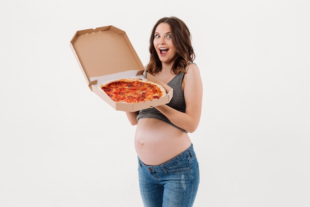 Удивленная беременная женщина, держащая пиццу.