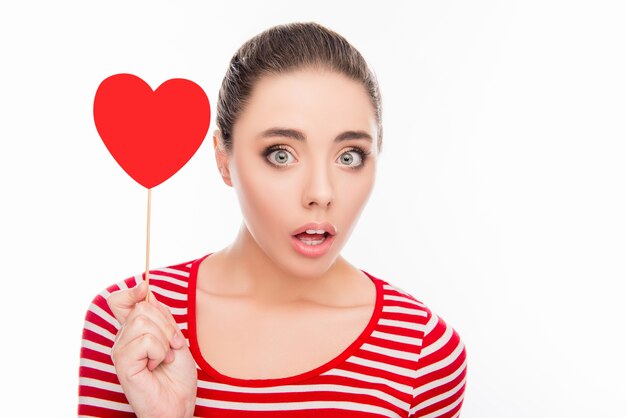 Surprised pretty girl holding red paper heart on stick