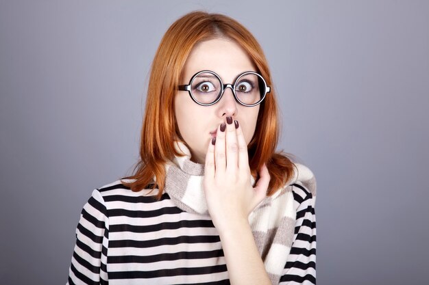 Surprised red-haired girl in glasses and scarf. 