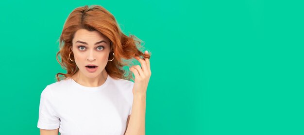 Surprised redhead girl with curly hair on blue background surprise Woman isolated face portrait banner with copy space