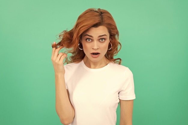 surprised redhead girl with curly hair on blue background surprise