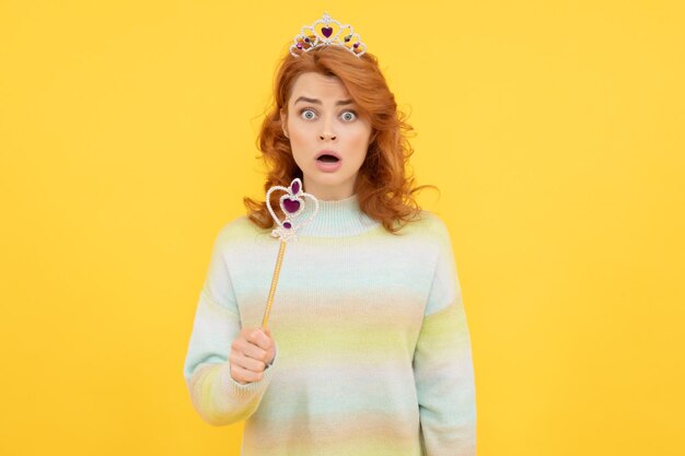 Surprised redhead woman in queen crown with magic wand surprise