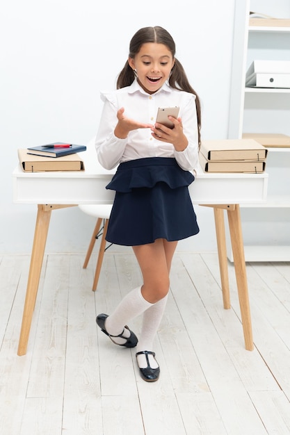 Surprised school girl messaging at the desk school girl messaging on phone