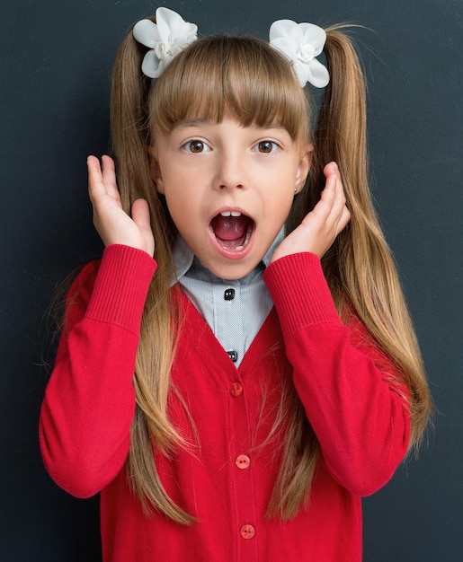 Photo surprised schoolgirl at the chalkboard background in class back to school concept