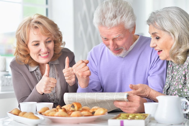 Surprised senior people reading newspaper while drinking tea