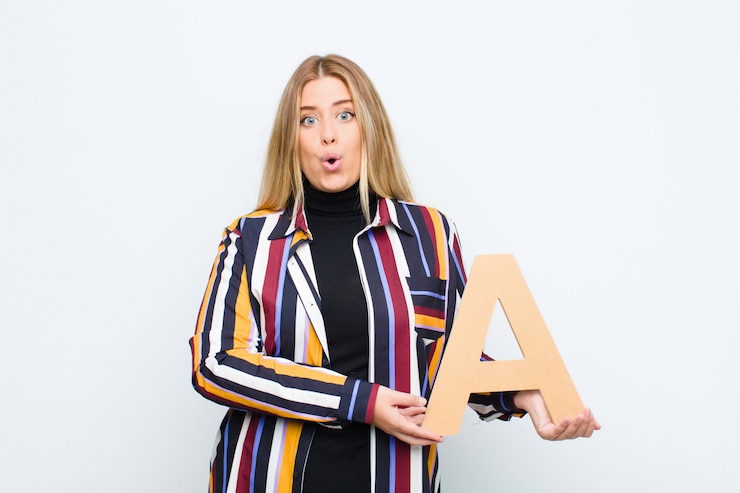 फोटो surprised, shocked, amazed, holding the letter a of the alphabet to form a word or a sentence.