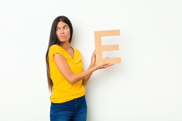 surprised, shocked, amazed, holding the letter E of the alphabet to form a word or a sentence.