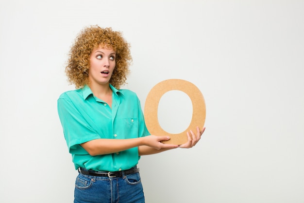 surprised, shocked, amazed, holding the letter O of the alphabet to form a word or a sentence.