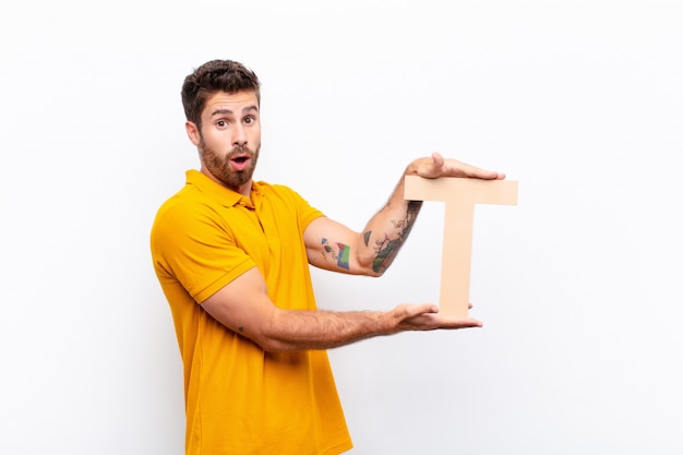 surprised, shocked, amazed, holding the letter T of the alphabet to form a word or a sentence.