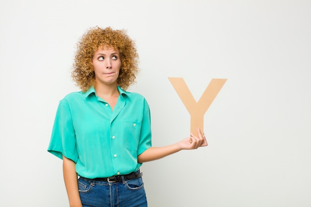 surprised, shocked, amazed, holding the letter Y of the alphabet to form a word or a sentence.