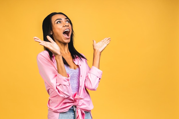 Surprised shocked amazed young african american woman stands in
big shopping mall glad to see big discounts on clothes expresses
shock going to spend much money today