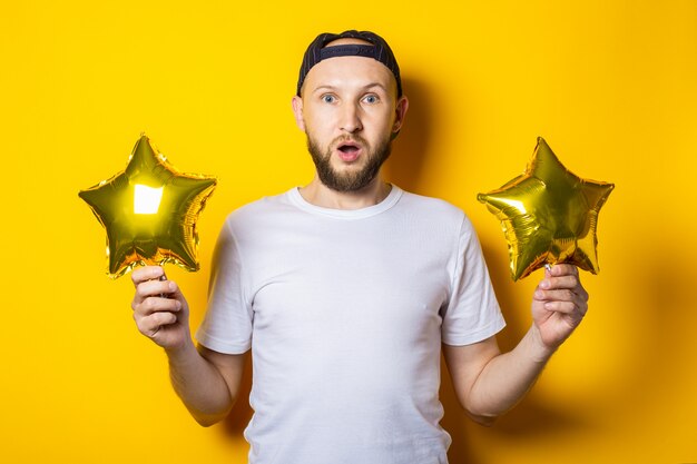 Surprised shocked bearded young man holding air balloons