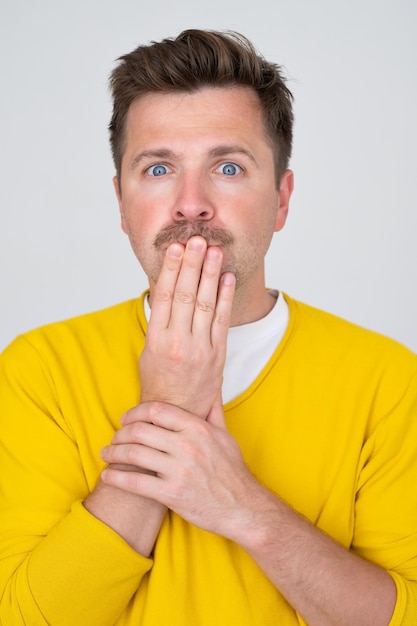 Surprised and shocked caucasian man covering mouth with hands