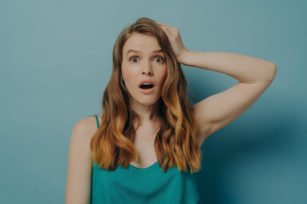 Photo surprised and shocked caucasian woman being amazed with wide open eyes and mouth isolated on blue