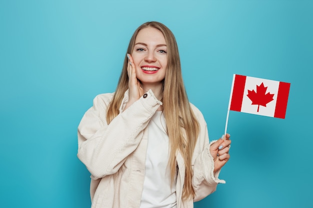 Surprised student girl smiling and holding a small canada flag and looking to camera