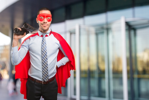 Surprised super businessman using a binoculars